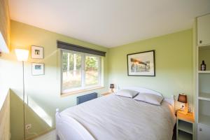 a bedroom with a white bed and a window at Le Chalet in Vresse-sur-Semois