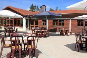an outdoor patio with tables and chairs and umbrellas at Azureva Métabief in Métabief