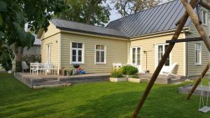 a small yellow house with a deck in the yard at Kuressaare Family and Garden Apartments in Kuressaare