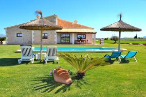 een tuin met een huis en een zwembad met stoelen bij Villa Flor de Sal 178 by Mallorca Charme in Muro