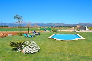 een tuin met een zwembad en enkele stoelen en bloemen bij Villa Flor de Sal 178 by Mallorca Charme in Muro