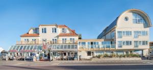 un grand bâtiment avec des tables et des chaises devant lui dans l'établissement Hotel Victoria, à Bergen aan Zee