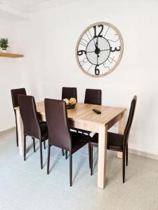 mesa de comedor con sillas y reloj en la pared en Apartamento completo Plaza España II, en Benidorm