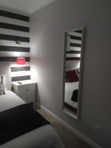 ナザレにあるFerhouseDreams-Praiaのベッドルーム1室(鏡付きベッド1台、ベッドサイドサイドサイドサイドサイド付)