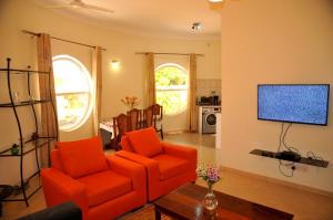 a living room with an orange chair and a television at Victoria Lake View Guesthouse & Safaris in Entebbe