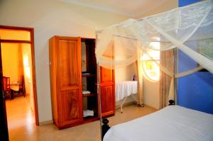 a bedroom with a canopy bed and a mirror at Victoria Lake View Guesthouse & Safaris in Entebbe