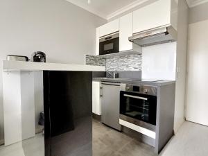a kitchen with stainless steel appliances and white cabinets at studio tout confort près de Disney in Serris