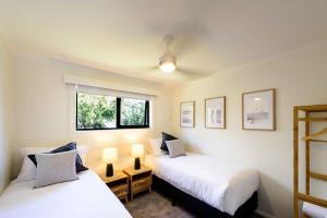 two beds in a room with two lamps and a window at Georges Bay Apartments in St Helens