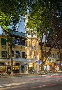 a building on the side of a street with trees at Silk Path Boutique Hanoi in Hanoi