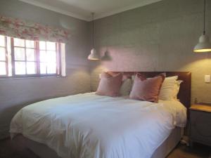 a bedroom with a bed with white sheets and pillows at Critchley Hackle Dullstroom Leisure in Dullstroom