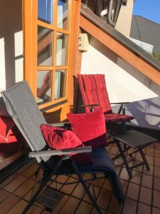2 Stühle mit roten Kissen auf dem Balkon in der Unterkunft Haus am Römerbad in Bad Kleinkirchheim