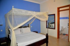 a bedroom with a canopy bed in a blue room at Victoria Lake View Guesthouse & Safaris in Entebbe