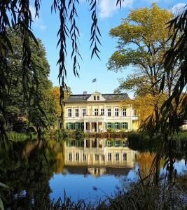 a building reflected in the water of a lake at Ferienwohnung Papenmühle am Kurpark in Bad Freienwalde