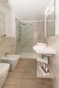 een witte badkamer met een wastafel en een douche bij Hotel Da Si-Si in Gemona del Friuli