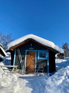 Cabaña de madera con techo cubierto de nieve en Joängets Fjällgård, en Sälen