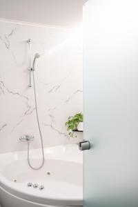 a bathroom with a bath tub with a shower at CHROMA FASHION ROOMS & APARTMENTS in Athens