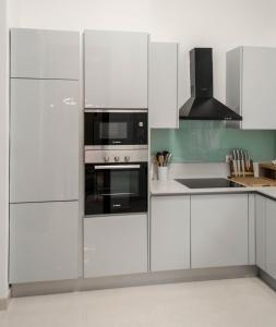 a kitchen with white cabinets and black appliances at Clayhall by SRS in Lagos