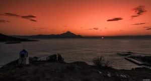 a sunset over a body of water with a lighthouse at House Chrysoula Mitsokopi in Sarti
