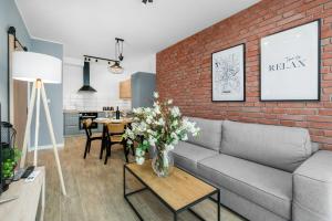 a living room with a couch and a brick wall at Premium Apartments Poznań Airport by Renters in Poznań