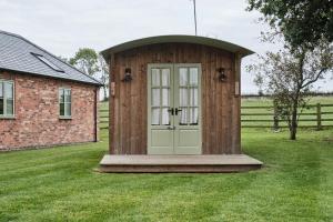 a wooden shed with a door in a field at Bridge House Barn in Kibworth Harcourt