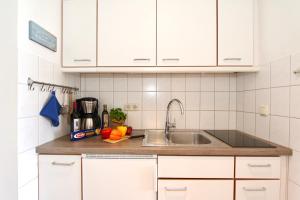 - une cuisine avec des placards blancs et un évier dans l'établissement Ferienwohnung Strandperle Haus Loreley, à Sankt Peter-Ording