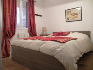 1 dormitorio con 1 cama con cortinas rojas y ventana en Un petit coin de Paradis, en Mazan