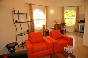 a living room with two orange chairs and a table at Victoria Lake View Guesthouse & Safaris in Entebbe