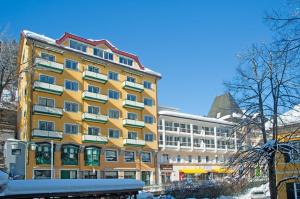 un gran edificio amarillo con nieve delante en Residenz Lothringen by AlpenTravel, en Bad Gastein