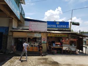 Um homem está em frente a um edifício. em Hotel Alifah 2 em Tangerang