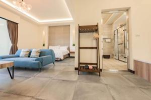a living room with a blue couch and a bed at 蘴旅民宿 in Chishang