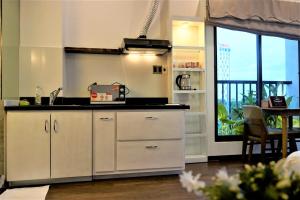 a kitchen with white cabinets and a sink and a window at Oasis Hotel & Apartment in Da Nang