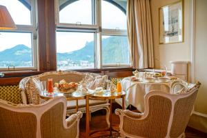a dining room with a table and chairs and windows at Hotel Schloss Mönchstein in Salzburg