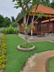 a garden with a house with a tree and grass at Medori Putih Homestay in Uluwatu