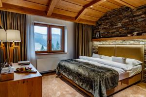 sypialnia z dużym łóżkiem i kamienną ścianą w obiekcie Grandhotel Tatra w mieście Velké Karlovice