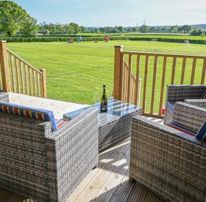 een terras met een tafel en stoelen en een veld bij Midleydown Luxury Glamping in Exeter
