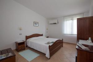 een slaapkamer met een bed, een dressoir en een bureau bij Hotel Ispinigoli in Dorgali
