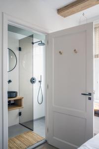 uma casa de banho com uma cabina de duche em vidro e uma porta de vidro. em Studios at the canal em Amsterdã