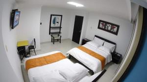 a hotel room with two beds and a chair at Hotel Centenario Plaza in Belén