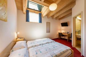a bedroom with two beds and a desk and a window at Hotel La Perla in SantʼAntonino