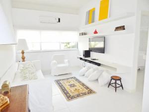 a white living room with white furniture and a tv at Leblon House I in Rio de Janeiro