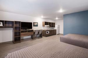 a bedroom with a bed and a desk with a television at WoodSpring Suites Detroit Madison Heights in Madison Heights