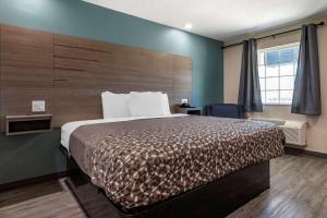 a bedroom with a large bed with a wooden headboard at Rodeway Inn in Caldwell