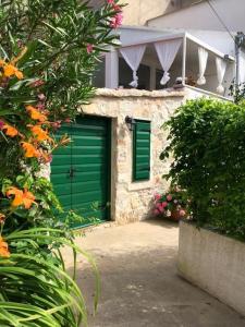 una casa con una porta verde del garage e dei fiori di Apartment Aduro a Šibenik