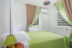 a bedroom with a green bed and a window at Bungalow de 2 chambres avec terrasse amenagee et wifi a Riviere Salee a 9 km de la plage in Rivière-Salée