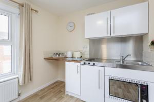 a kitchen with white cabinets and a sink at Blackberry - Stylish Self-Contained Flats in Soton City Centre in Southampton