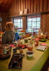 Una mujer sentada en una mesa con comida. en Linkkumylly Cottages en Mäntyharju