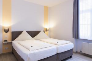 a bedroom with two beds with white sheets and a window at Hotel Alte Mühle in Chemnitz