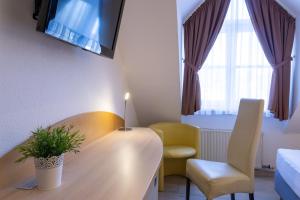 a room with a table and a chair and a tv at Hotel Alte Mühle in Chemnitz