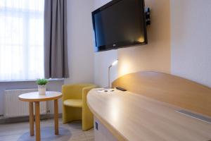 a hotel room with a desk with a tv on the wall at Hotel Alte Mühle in Chemnitz