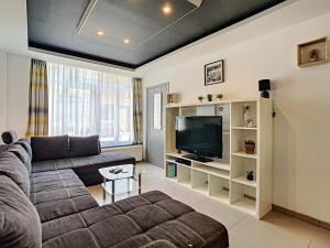 Una sala de estar con un sofá y un televisor. en Au Fil de l Eau, en Yvoir